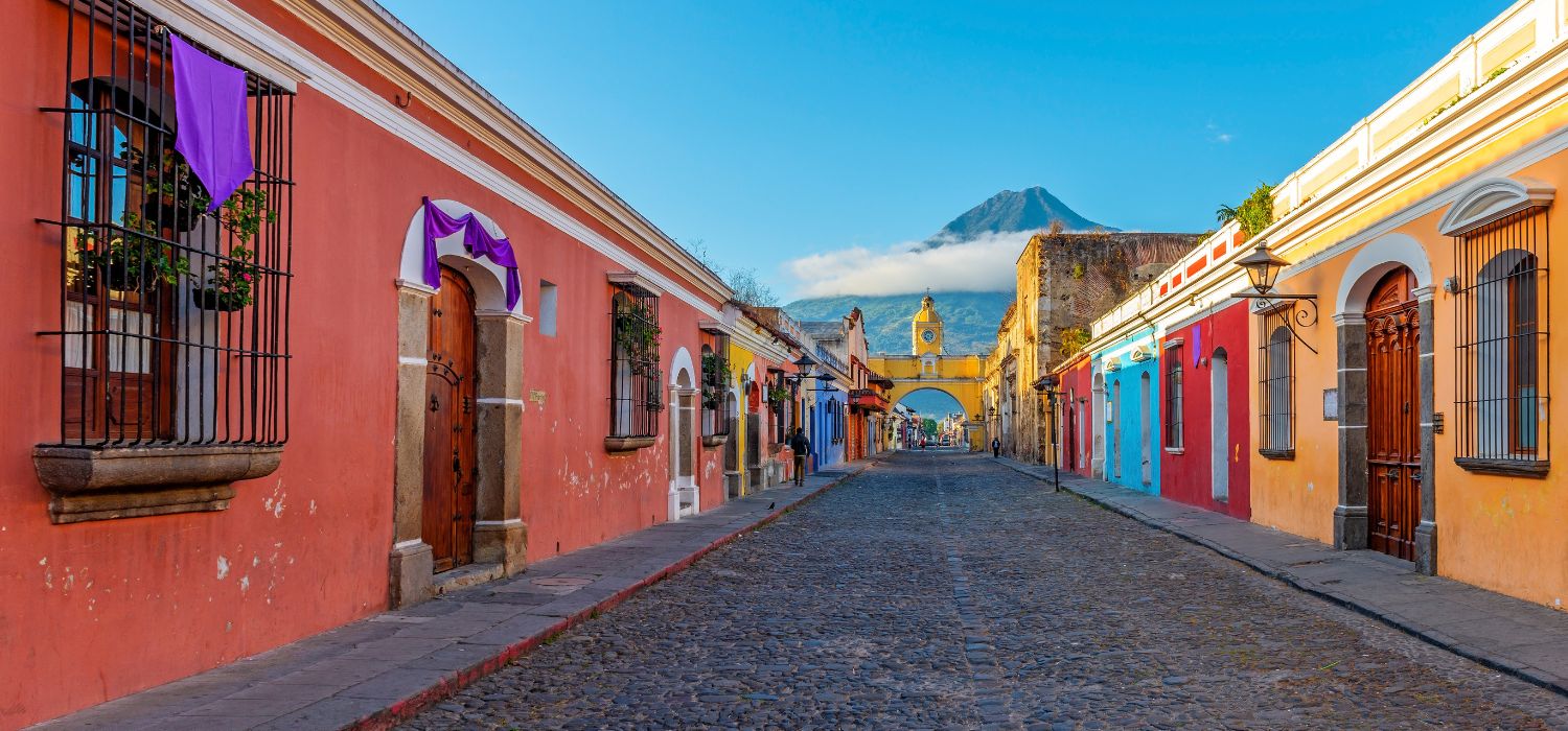 Cityscape of Antigua city at sunrise with the Santa Catalina arch and Agua volcano, Guatemala.