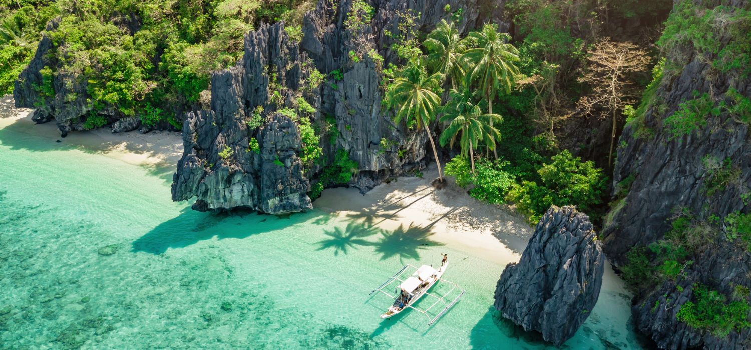 Beautiful Entalula Island Beach Lagoon with typical filipino Balangay Boats. Aerial Drone Point of View. Bacuit Bay, Mimaropa, El Nido, Palawan, Philippines, Asia