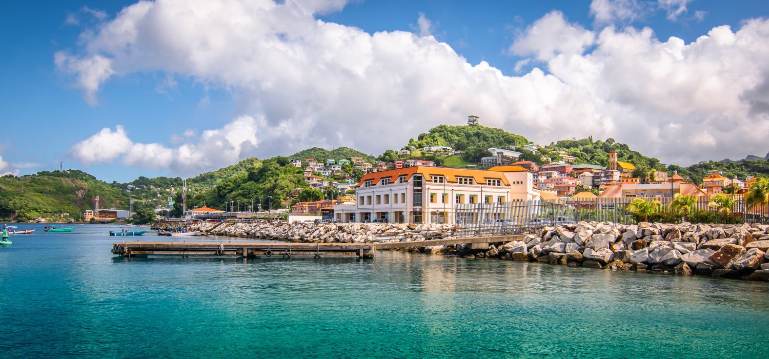 Beautiful horizontal image of St George's, cruise port in Grenada. Blue sky with white clouds, waterfront and bright buildings along the coastline.